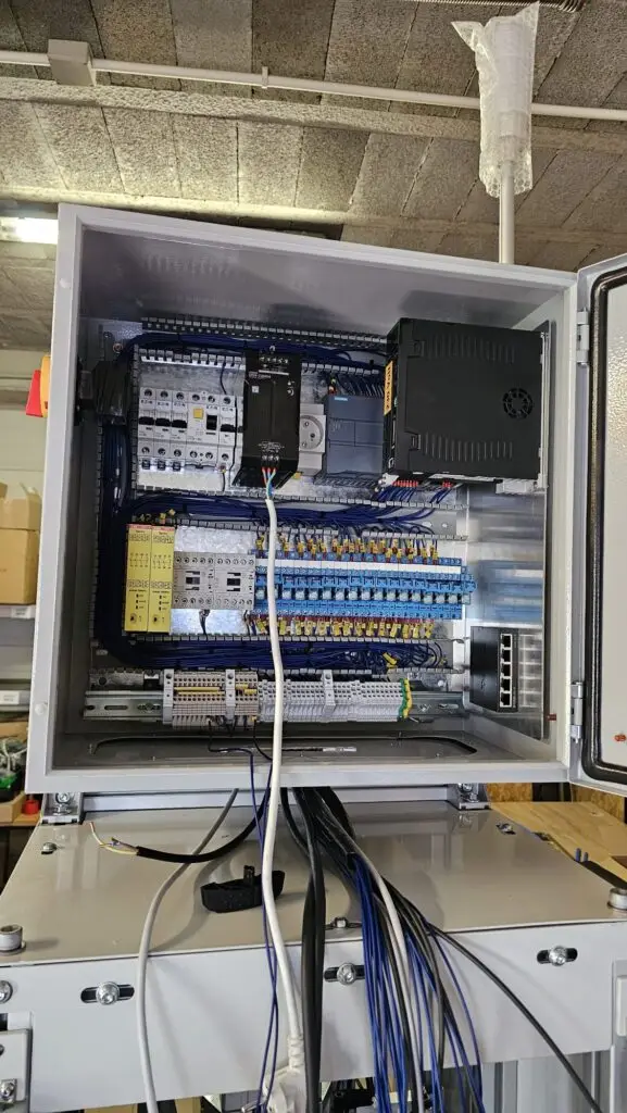 zdjęcie przedstawiające szafęsterowniczną podczas montażu wyposażoną w sterownik PLC firmy Siemens oraz serwo napęd HIWIN